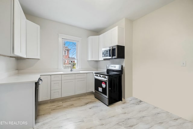 112 E Inskip Dr, Knoxville, TN 37912 - kitchen with stainless steel appliances, a sink, light countertops, white cabinetry, and light marble finish flooring