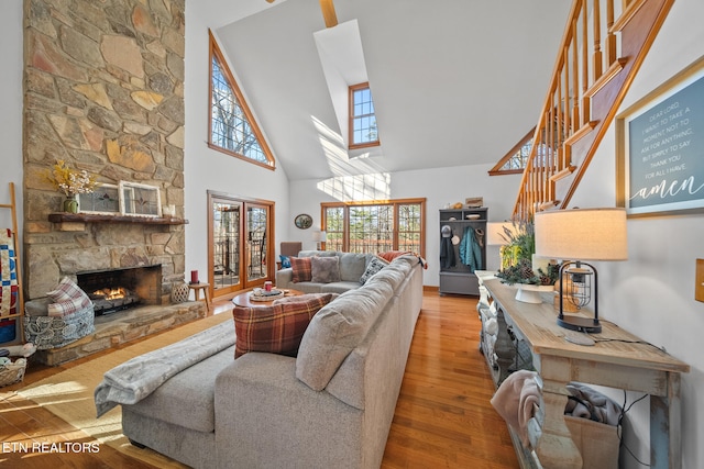 living room with a fireplace, light hardwood / wood-style floors, and a high ceiling