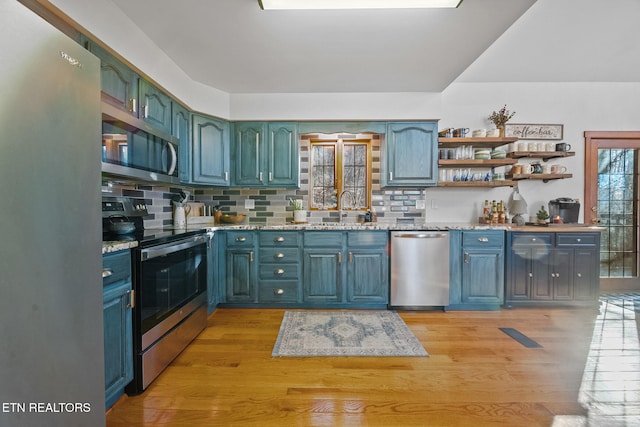 kitchen featuring stainless steel appliances, sink, light hardwood / wood-style flooring, and backsplash