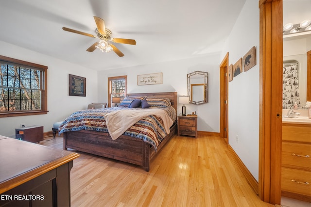 bedroom with ceiling fan, ensuite bath, and light hardwood / wood-style flooring