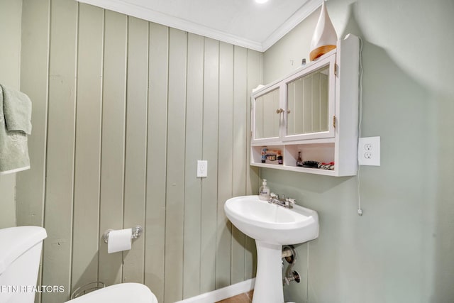 bathroom featuring ornamental molding, sink, wood walls, and toilet