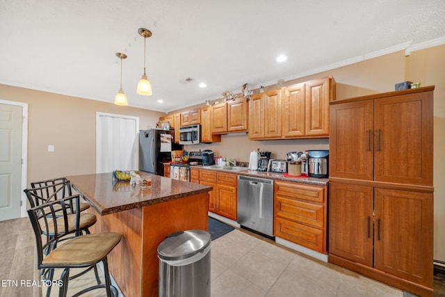 kitchen featuring a kitchen island, a breakfast bar, decorative light fixtures, ornamental molding, and stainless steel appliances