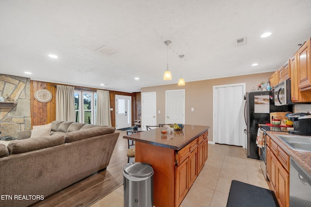 kitchen with hanging light fixtures, a center island, light tile patterned floors, stainless steel appliances, and a textured ceiling