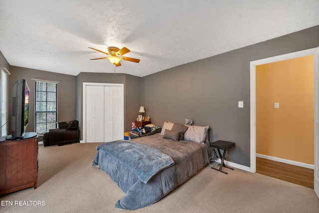 carpeted bedroom featuring ceiling fan, a closet, and a textured ceiling