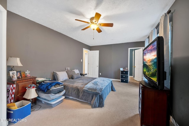 carpeted bedroom featuring ceiling fan and a textured ceiling