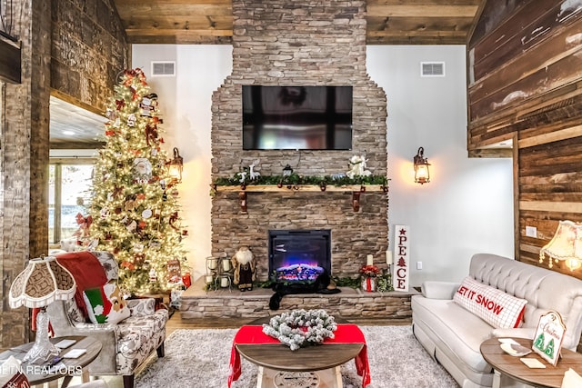 living room with wood-type flooring, a stone fireplace, and wooden ceiling