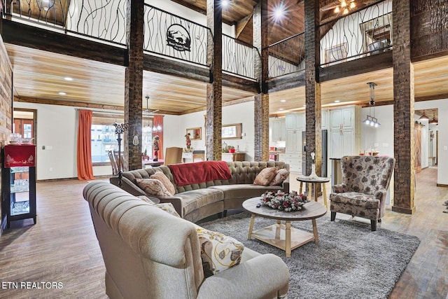 living room with decorative columns, a high ceiling, hardwood / wood-style floors, and wooden ceiling