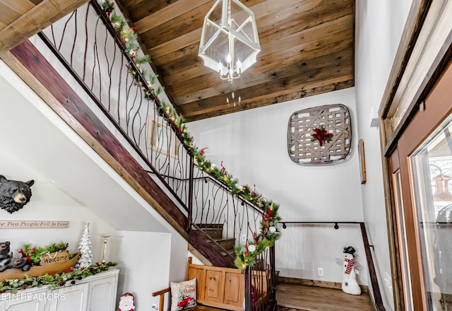 stairs with an inviting chandelier, a towering ceiling, wood ceiling, and hardwood / wood-style flooring