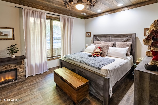 bedroom featuring a stone fireplace, wooden ceiling, and dark hardwood / wood-style floors