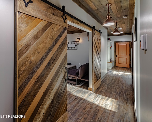 corridor featuring wood ceiling, a barn door, and dark hardwood / wood-style flooring