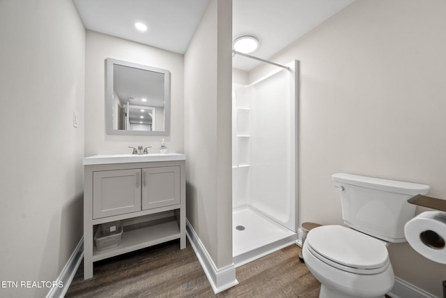 bathroom with hardwood / wood-style flooring, toilet, vanity, and walk in shower