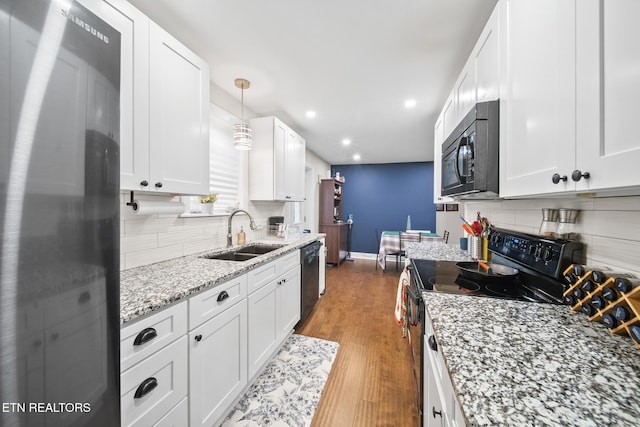 kitchen featuring sink, black appliances, hanging light fixtures, and white cabinets