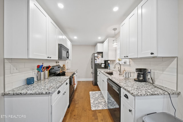 kitchen with sink, dark wood-type flooring, white cabinetry, black appliances, and light stone countertops