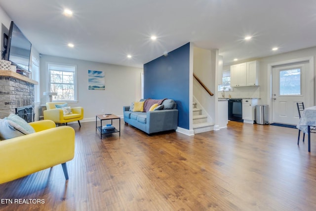 living room featuring a stone fireplace and light hardwood / wood-style flooring