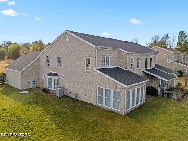 rear view of property with cooling unit and a yard