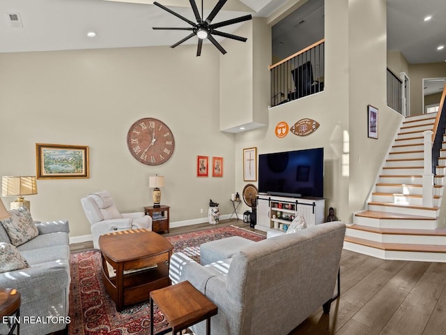 living room featuring a towering ceiling, dark hardwood / wood-style floors, and ceiling fan