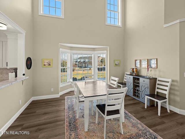 dining space featuring dark wood-type flooring and a high ceiling