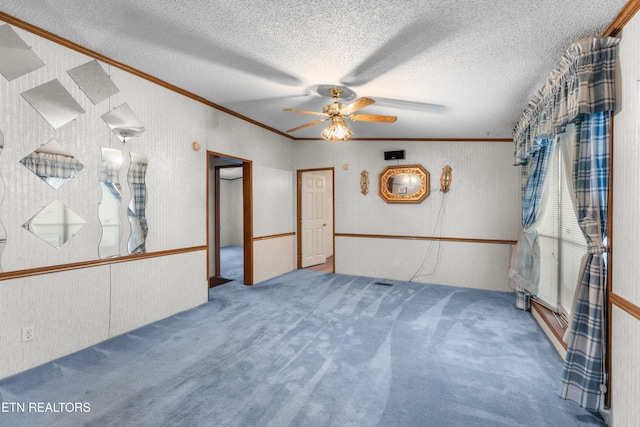 carpeted empty room with ceiling fan, crown molding, and a textured ceiling