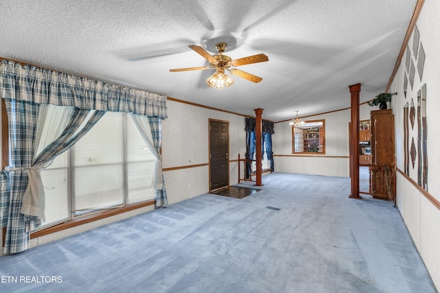 carpeted empty room featuring crown molding, ceiling fan, decorative columns, and a textured ceiling