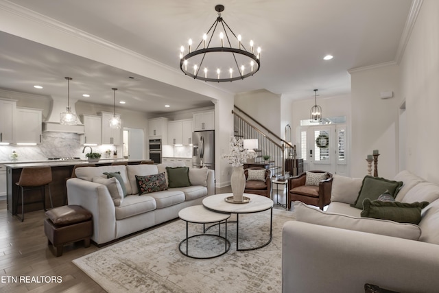 living room featuring hardwood / wood-style flooring, ornamental molding, and an inviting chandelier