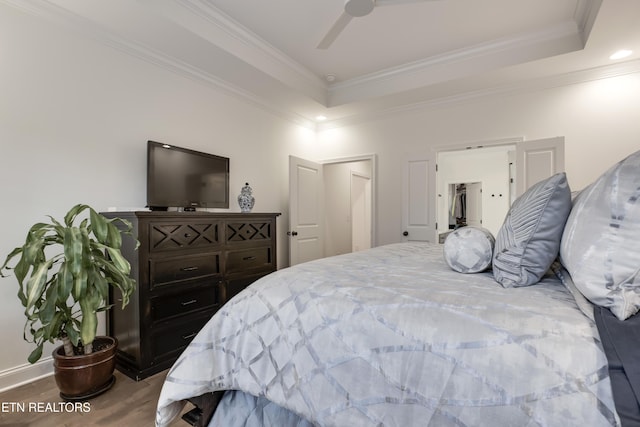 bedroom featuring hardwood / wood-style flooring, ceiling fan, crown molding, and a raised ceiling