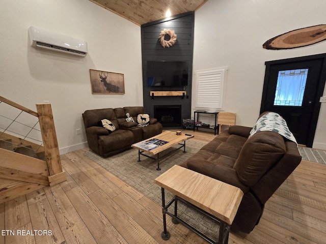 living room with wood ceiling, light hardwood / wood-style flooring, high vaulted ceiling, a wall unit AC, and a large fireplace