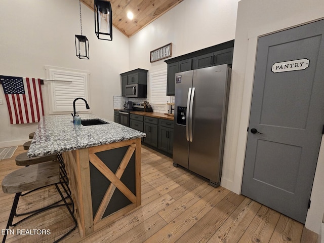 kitchen with sink, light stone counters, high vaulted ceiling, stainless steel appliances, and light hardwood / wood-style floors