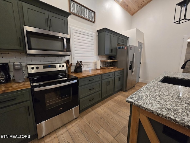 kitchen with sink, light hardwood / wood-style flooring, stainless steel appliances, and hanging light fixtures