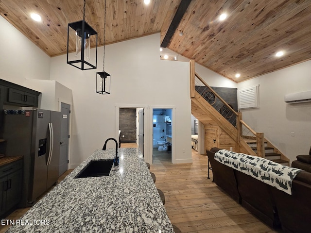 kitchen featuring sink, wood ceiling, light wood-type flooring, stainless steel fridge, and stone counters