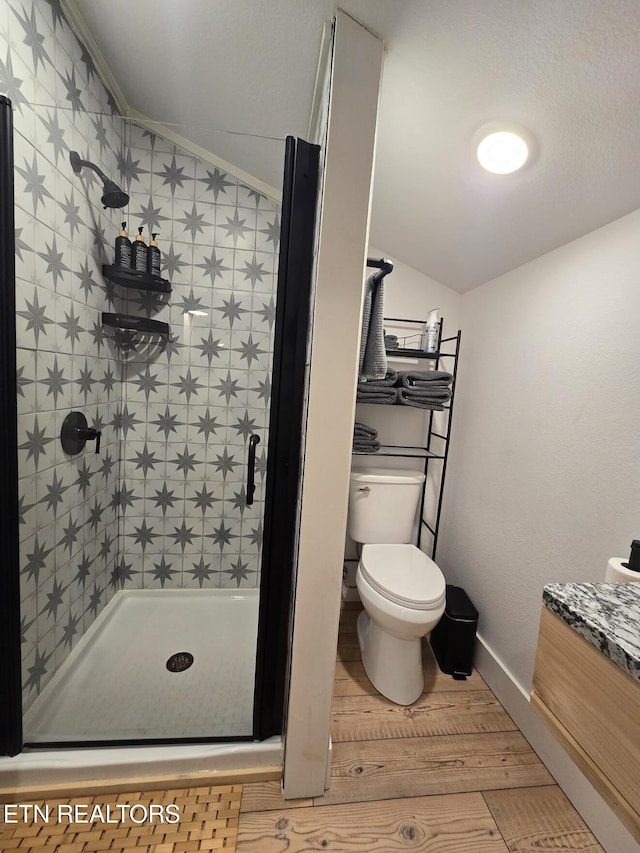 bathroom featuring wood-type flooring, lofted ceiling, ornamental molding, walk in shower, and toilet