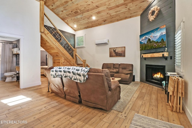living room with an AC wall unit, a large fireplace, wood ceiling, and light wood finished floors