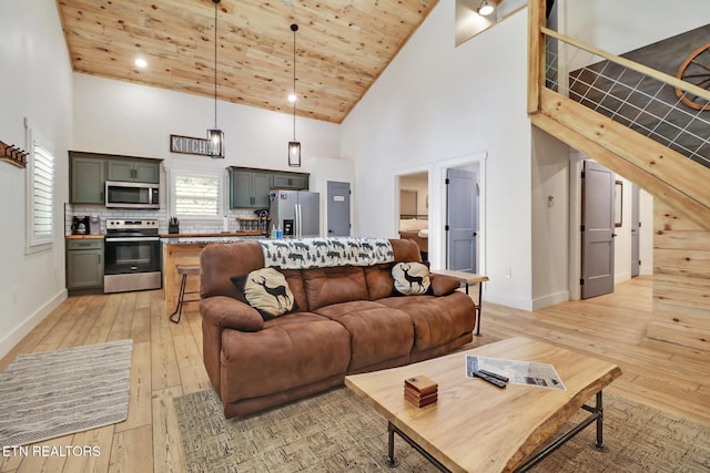 living area with high vaulted ceiling, baseboards, and light wood-style flooring