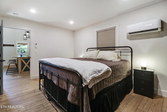 bedroom with light wood-style floors, baseboards, a wall mounted AC, and recessed lighting