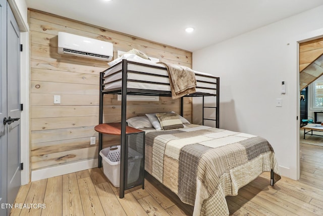 bedroom with light wood-style floors, recessed lighting, baseboards, and an AC wall unit