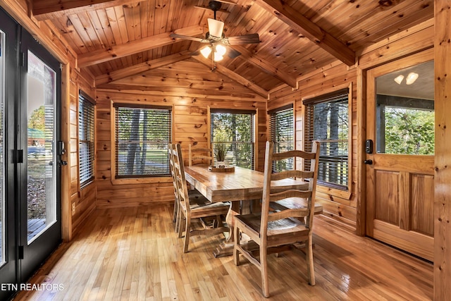 dining room with lofted ceiling with beams, wooden walls, light hardwood / wood-style floors, and wooden ceiling