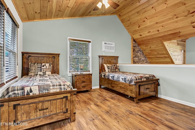 bedroom featuring lofted ceiling, light hardwood / wood-style floors, a wall unit AC, and wooden ceiling