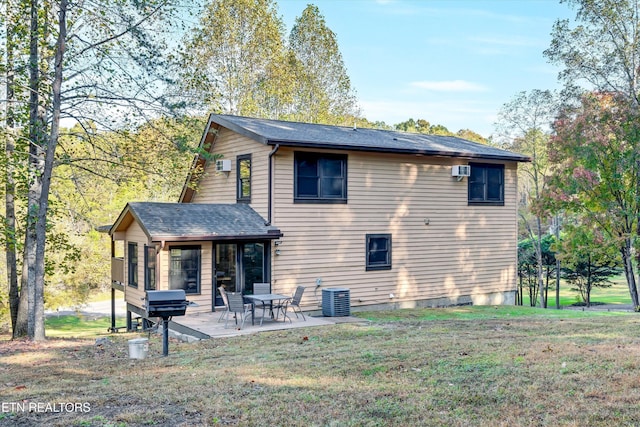 rear view of property with a lawn, a patio, and central air condition unit