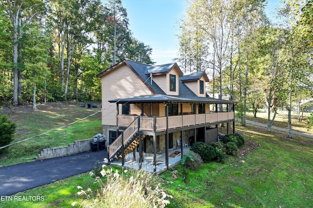 back of property with a wooden deck and a yard