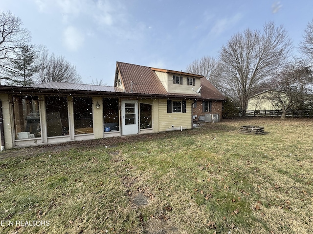 rear view of property featuring a fire pit and a lawn