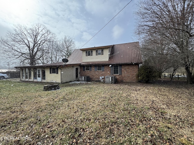 back of property featuring central AC, a fire pit, and a lawn