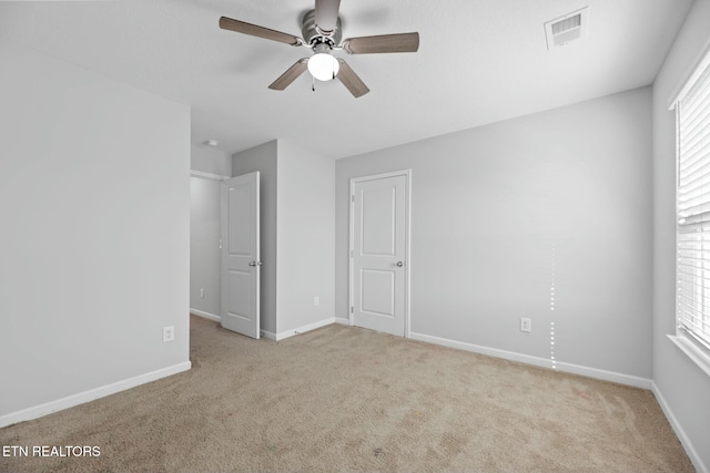 unfurnished bedroom featuring ceiling fan, light colored carpet, and multiple windows