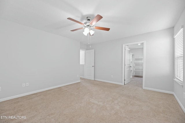 unfurnished bedroom featuring ceiling fan, light colored carpet, a closet, and a walk in closet