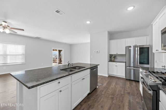 kitchen with an island with sink, appliances with stainless steel finishes, sink, and white cabinets