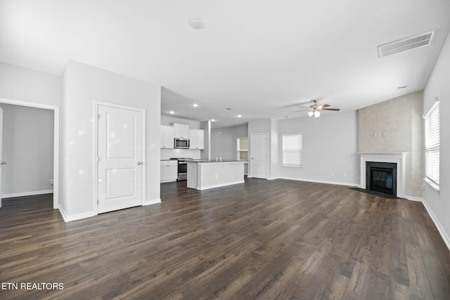 unfurnished living room featuring dark wood-type flooring and ceiling fan