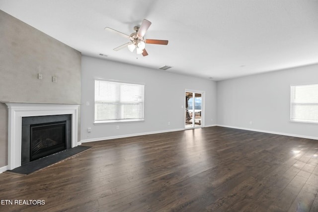 unfurnished living room featuring dark wood-type flooring and ceiling fan