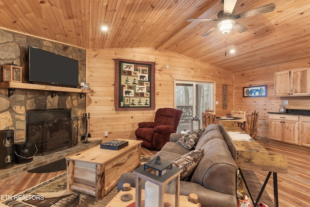 living room with light hardwood / wood-style flooring, lofted ceiling with beams, a stone fireplace, wooden ceiling, and wood walls