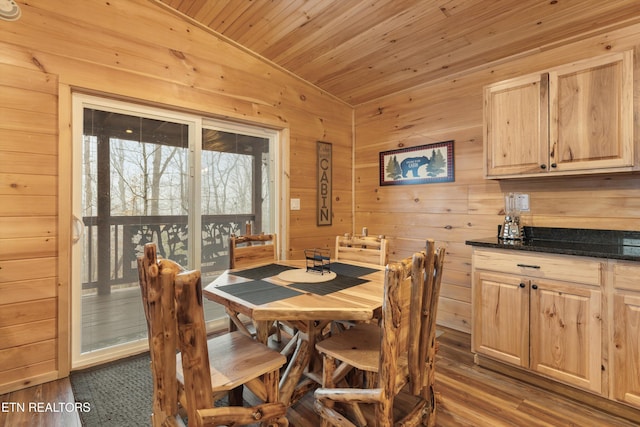 dining room featuring hardwood / wood-style floors, wooden ceiling, and wooden walls