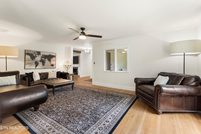 living room with ceiling fan, wood-type flooring, and ornamental molding