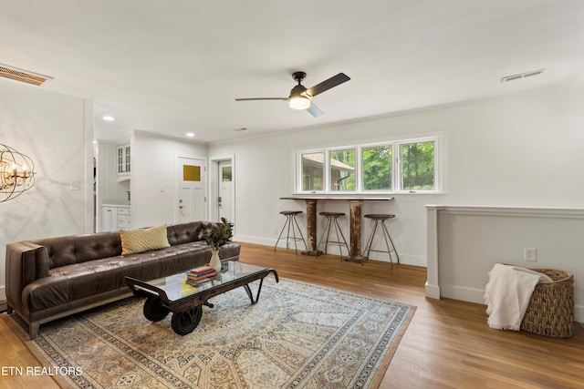 living room featuring ceiling fan with notable chandelier and light hardwood / wood-style flooring