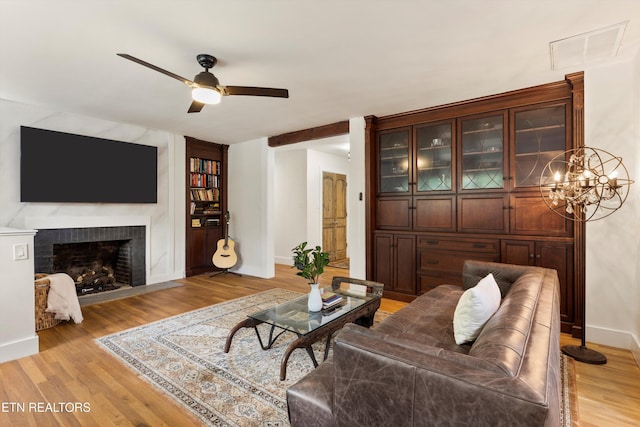 living room featuring ceiling fan, a fireplace, and light hardwood / wood-style flooring